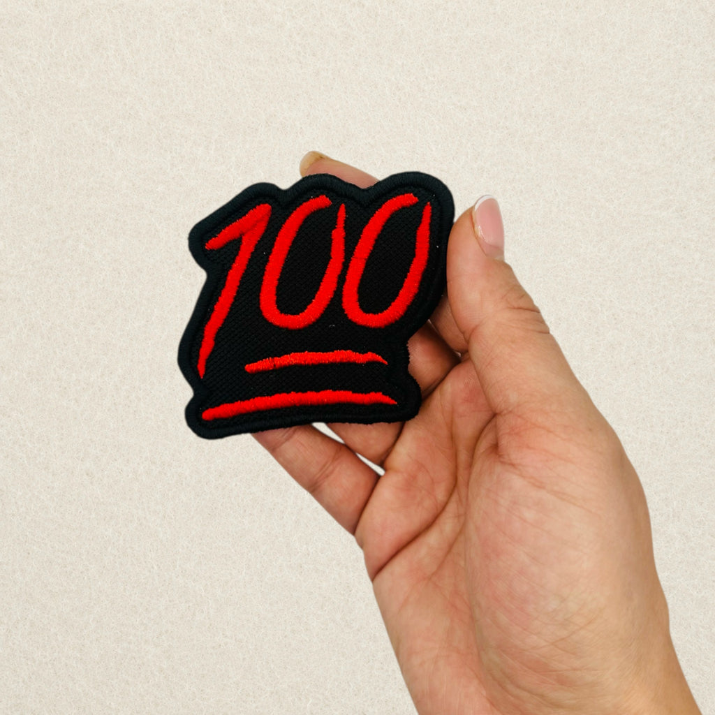 100 Emoji embroidered patch shown in hand to demonstrate its actual size.