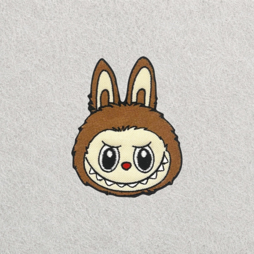 Brown Labubu embroidered patch displayed on a light grey felt background.