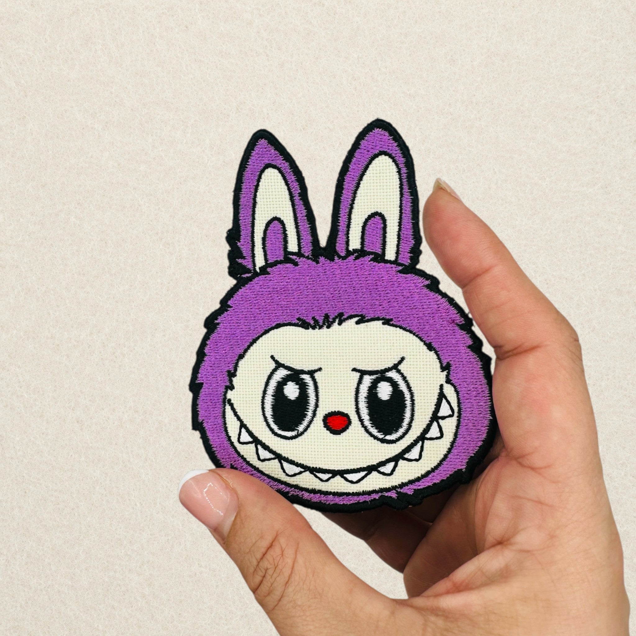 Purple Labubu embroidered patch shown in hand to demonstrate its actual size.
