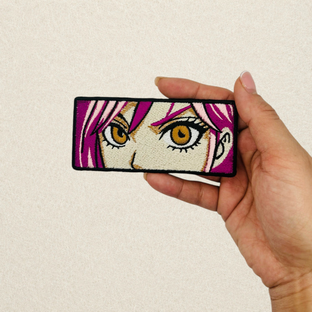 Anime Eyes embroidered patch shown in hand to demonstrate its actual size.