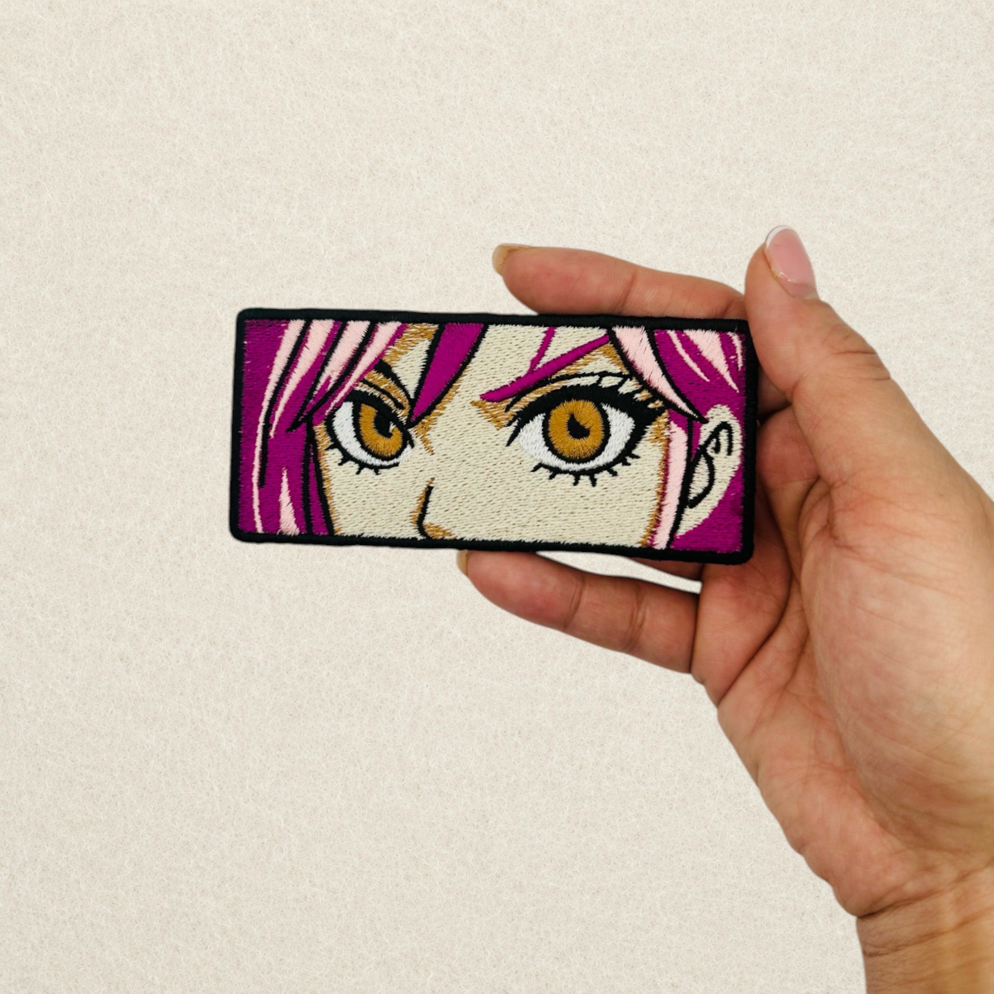 Anime Eyes embroidered patch shown in hand to demonstrate its actual size.