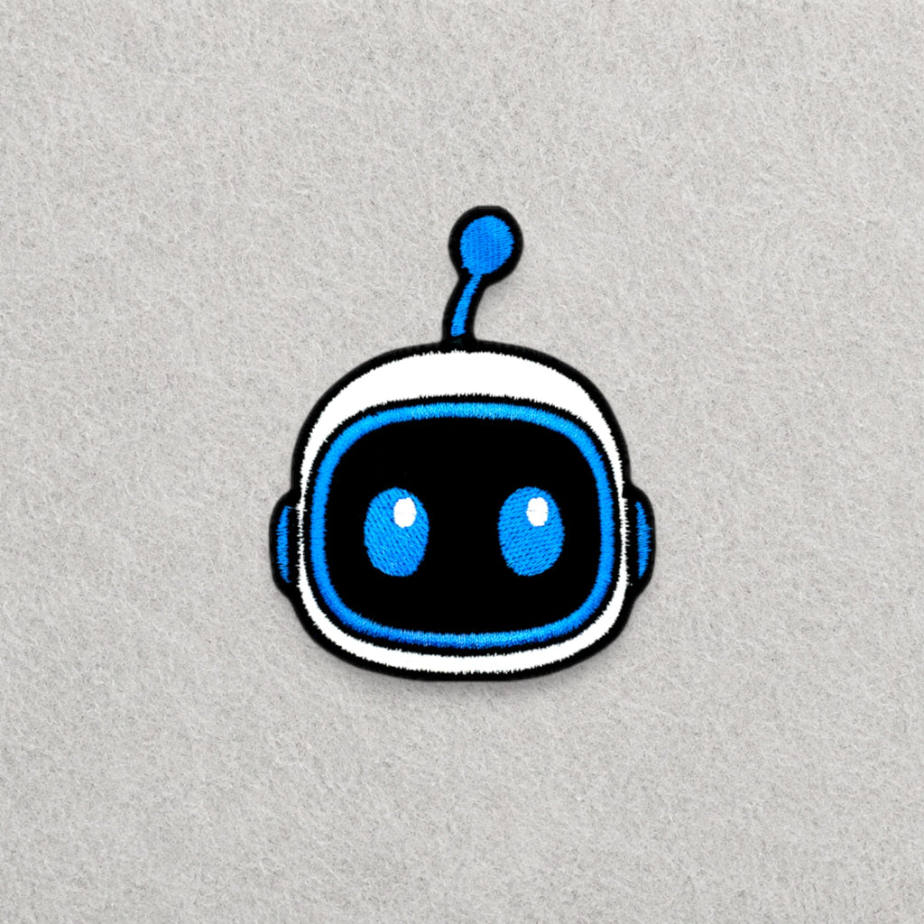 Astro Bot Head embroidered patch displayed on a light grey felt background.