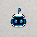 Astro Bot Head embroidered patch displayed on a light grey felt background.