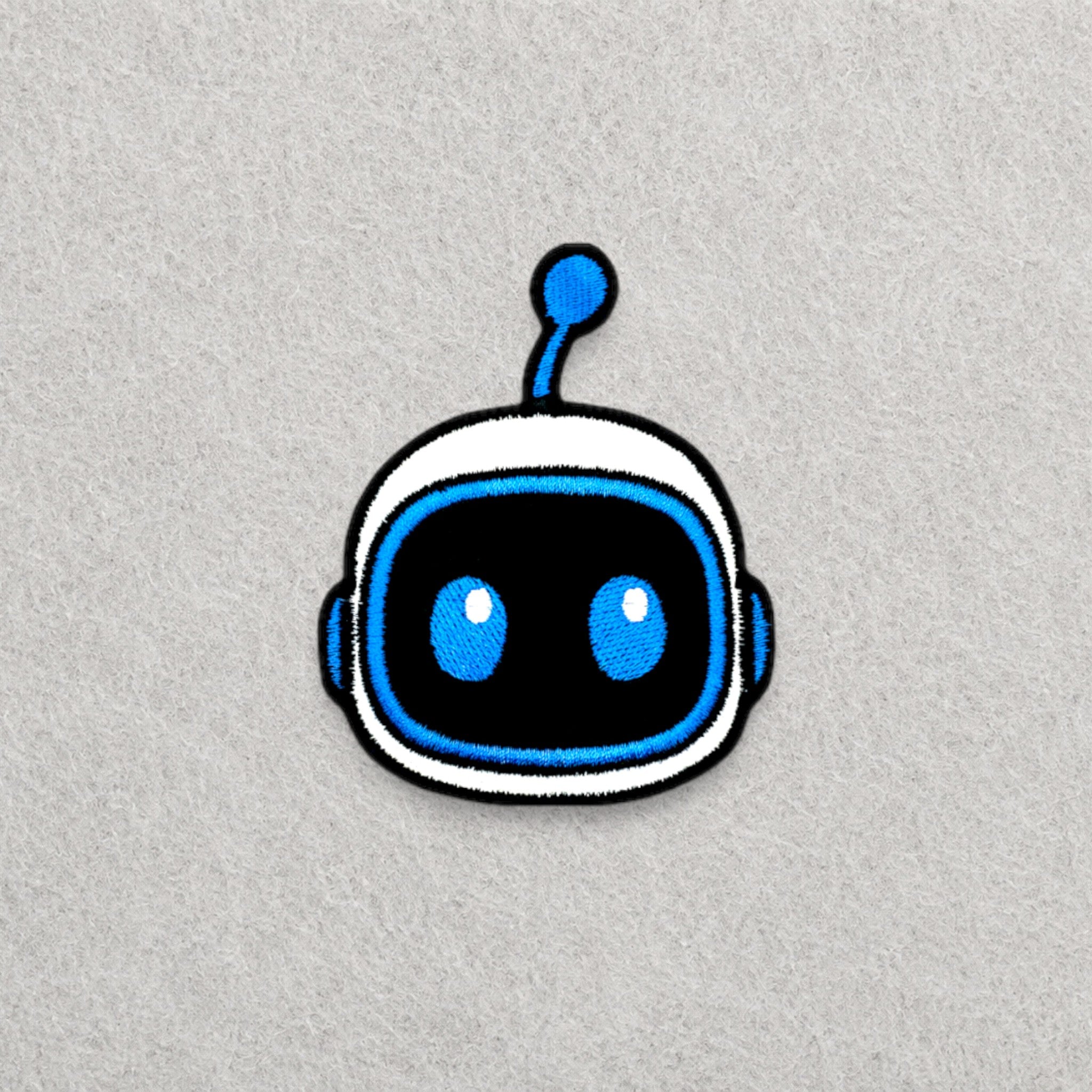 Astro Bot Head embroidered patch displayed on a light grey felt background.
