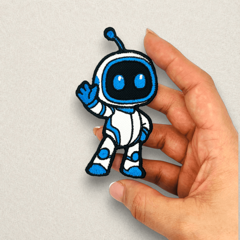 Astro Bot inspired embroidered patch held in hand to showcase the size, premium stitching, satin border and quality of a custom embroidered gaming patch.