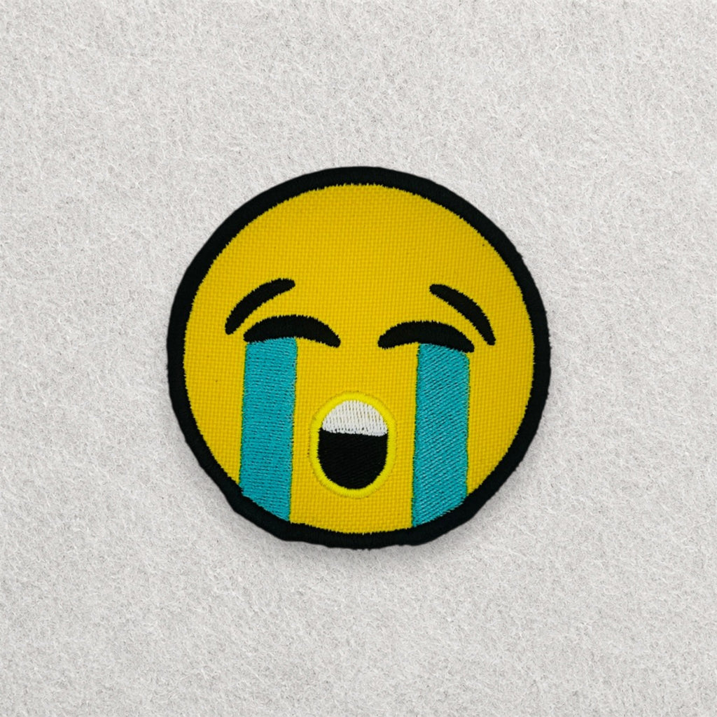 Crying Face Emoji embroidered patch displayed on a light grey felt background.