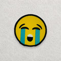 Crying Face Emoji embroidered patch displayed on a light grey felt background.