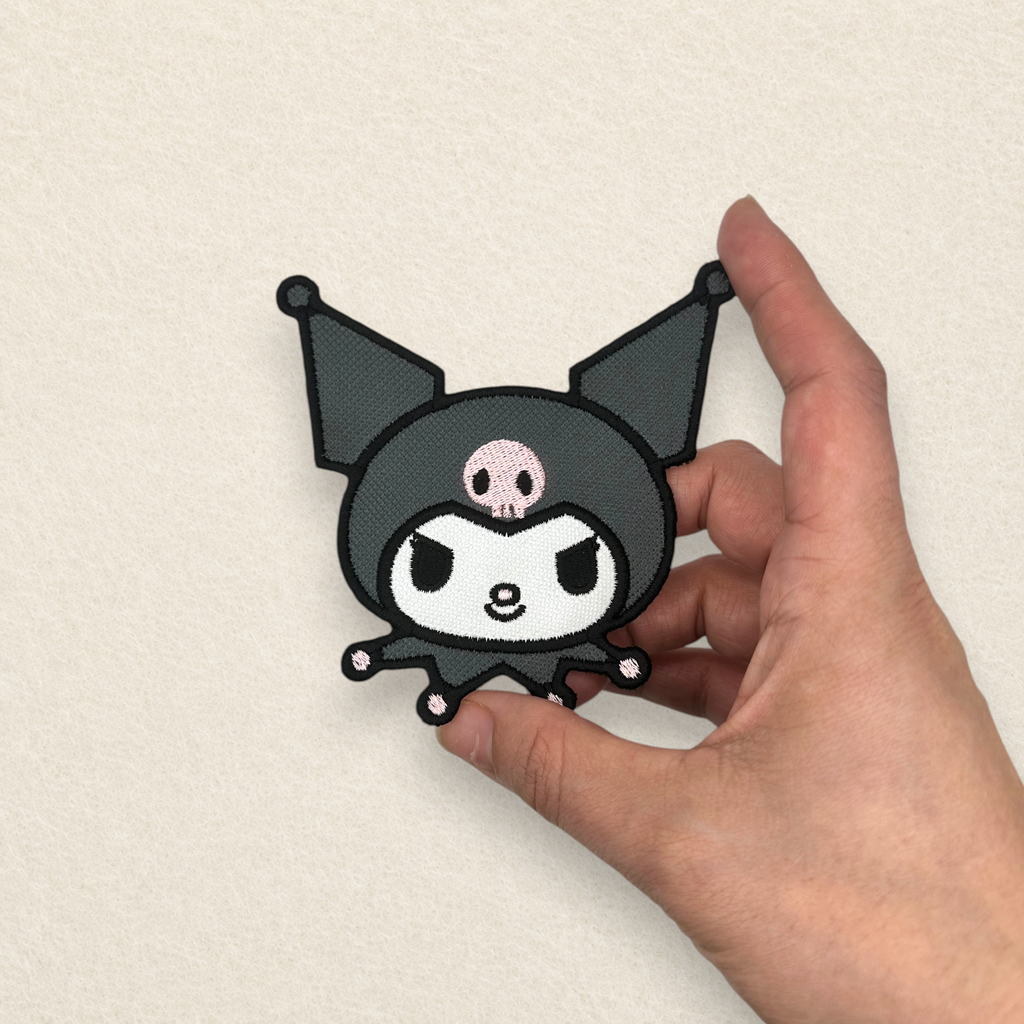 Close-up of a Kuromi inspired embroidered patch held in hand, showcasing the premium stitching, embroidered detail and finished size.