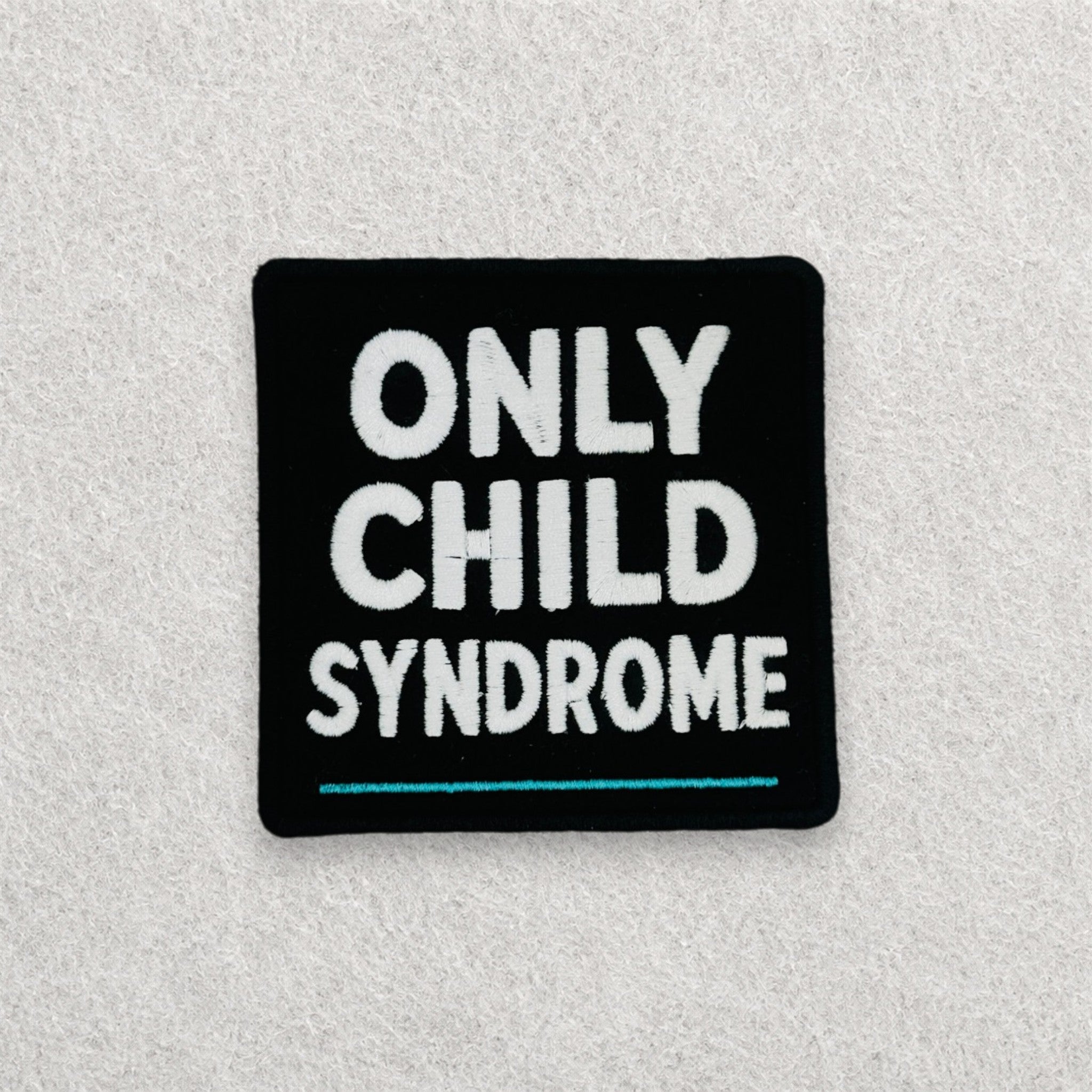 Only Child Syndrome embroidered morale patch displayed on a light grey felt background.