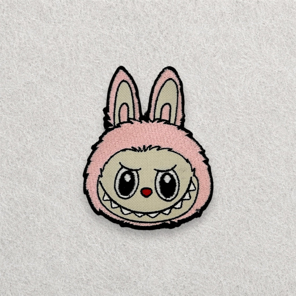 Pink Labubu embroidered patch displayed on a light grey felt background.