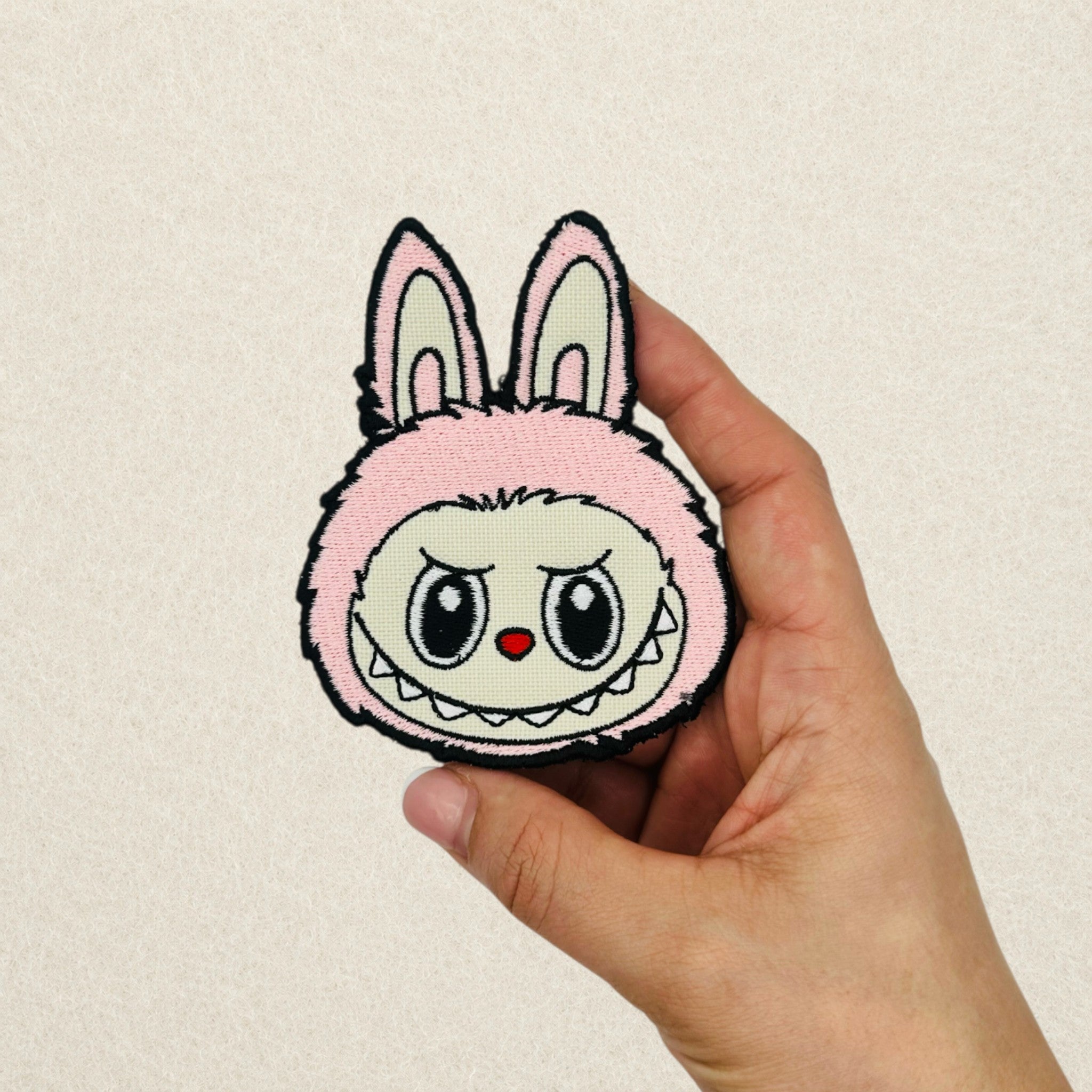 Pink Labubu embroidered patch shown in hand to demonstrate its actual size.
