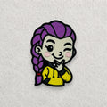 Rumi K-pop inspired embroidered patch featuring a cute winking character with purple braided hair and a yellow hoodie, finished with detailed stitching and a black embroidered border.