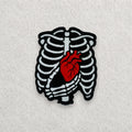 Skeleton Heart embroidered patch displayed on a light grey felt background.