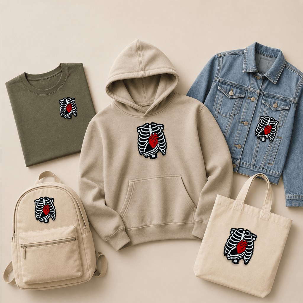 Skeleton rib cage embroidered patch with an exposed red heart displayed on a T-shirt, hoodie, denim jacket, backpack and tote bag, showing how a gothic anatomical patch looks on apparel and accessories.