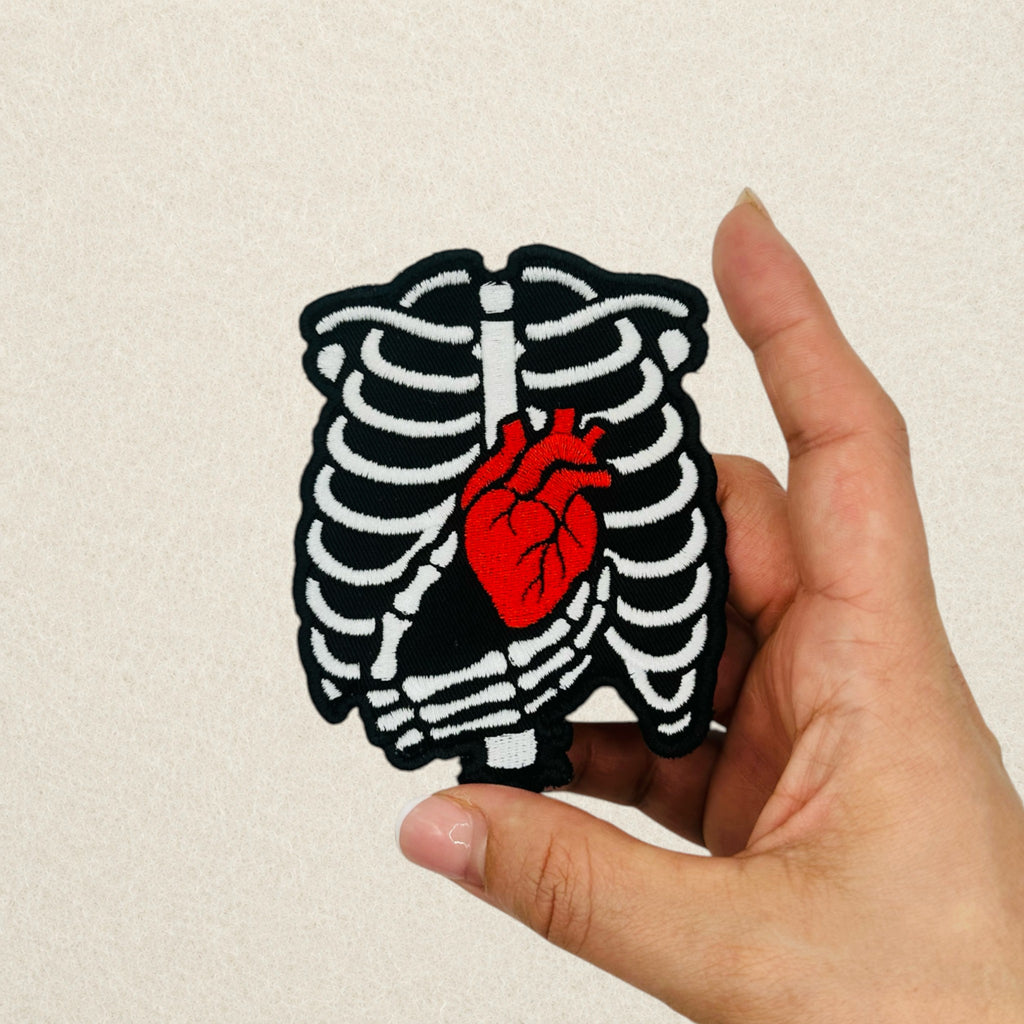 Skeleton Heart embroidered patch shown in hand to demonstrate its actual size.