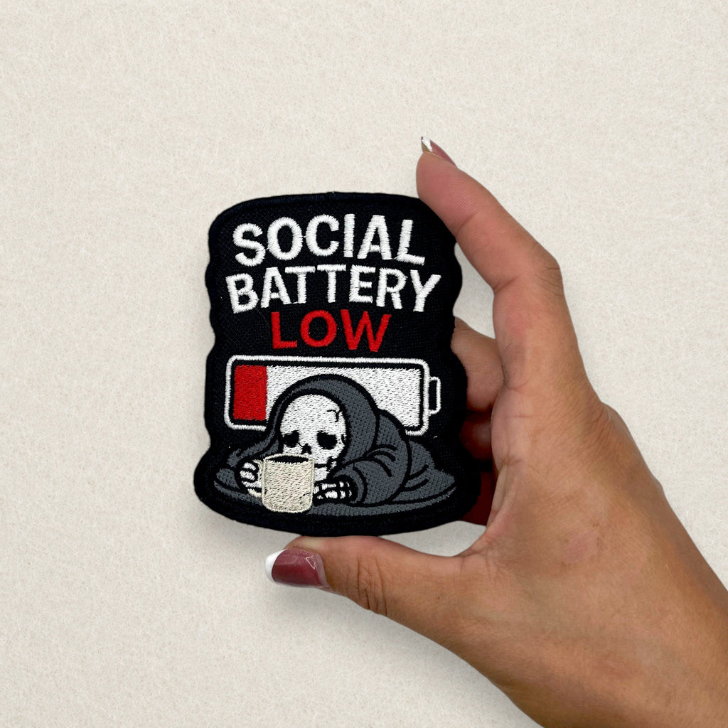 Social Battery Low embroidered patch with skeleton and low battery design shown in hand