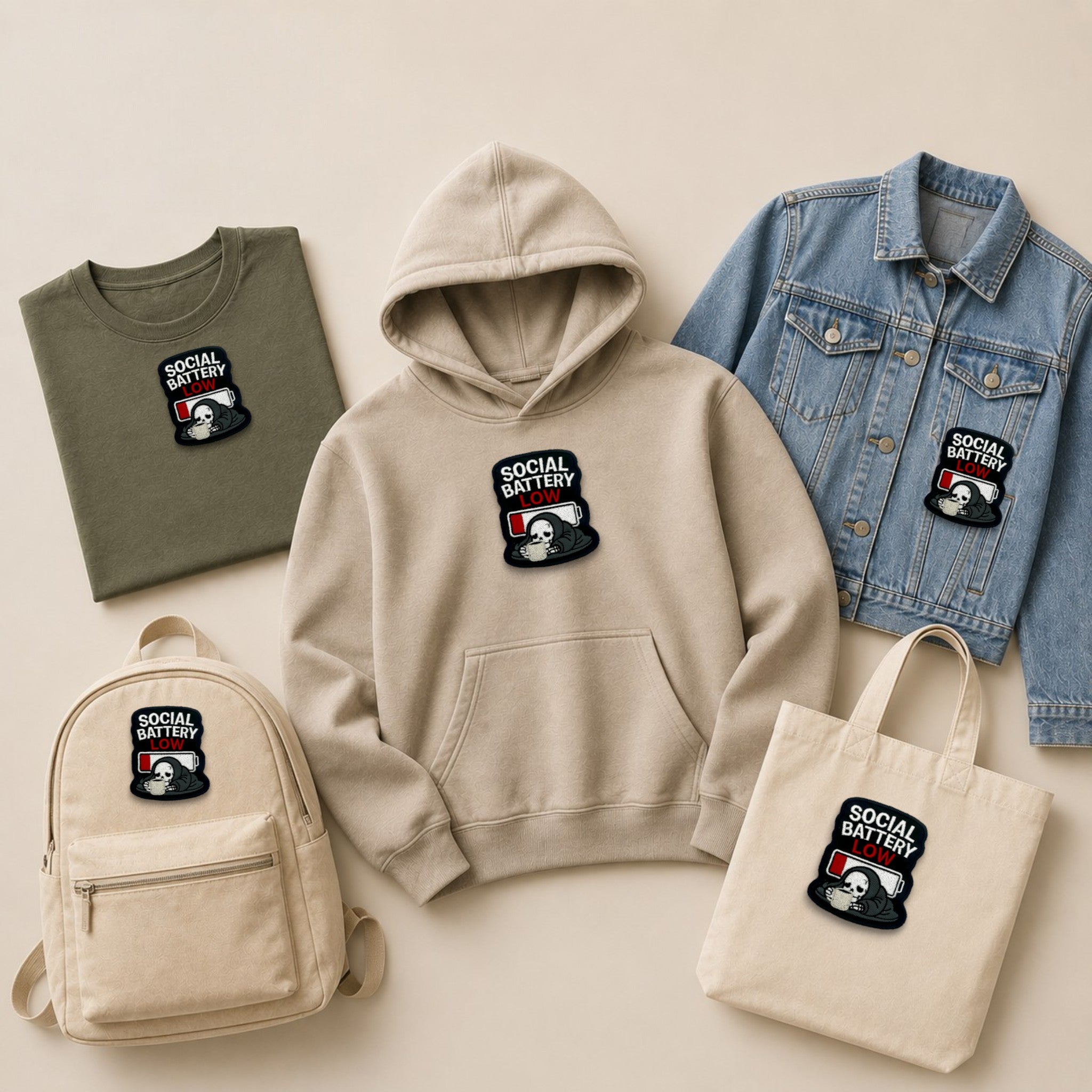 Social Battery Low embroidered patch shown on hoodie, T-shirt, denim jacket, backpack and tote bag