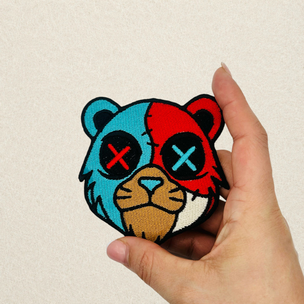 Split Face Bear embroidered patch shown in hand to demonstrate its actual size.