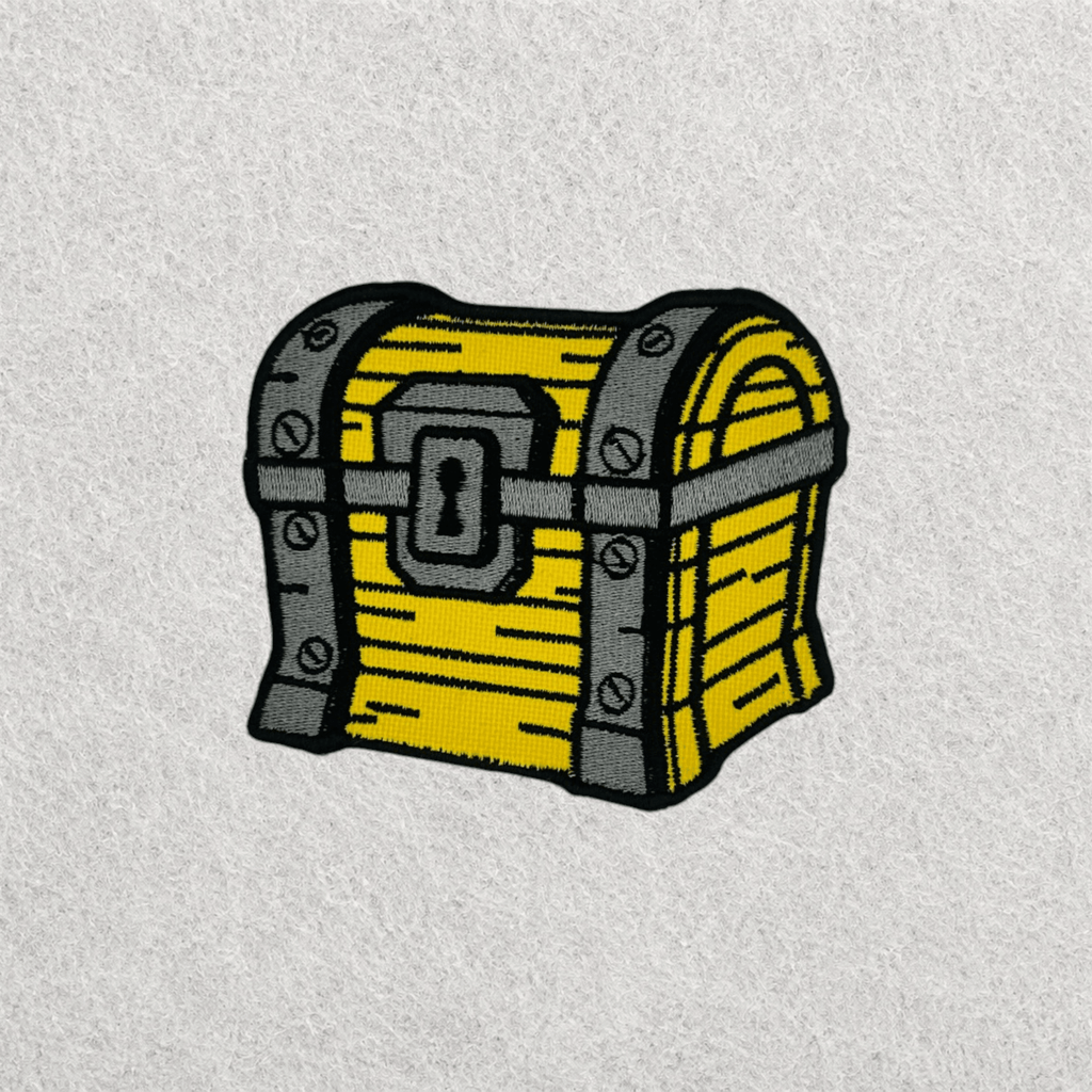 Treasure chest embroidered patch held in hand to showcase the size, stitching quality and detail of a custom embroidered patch.