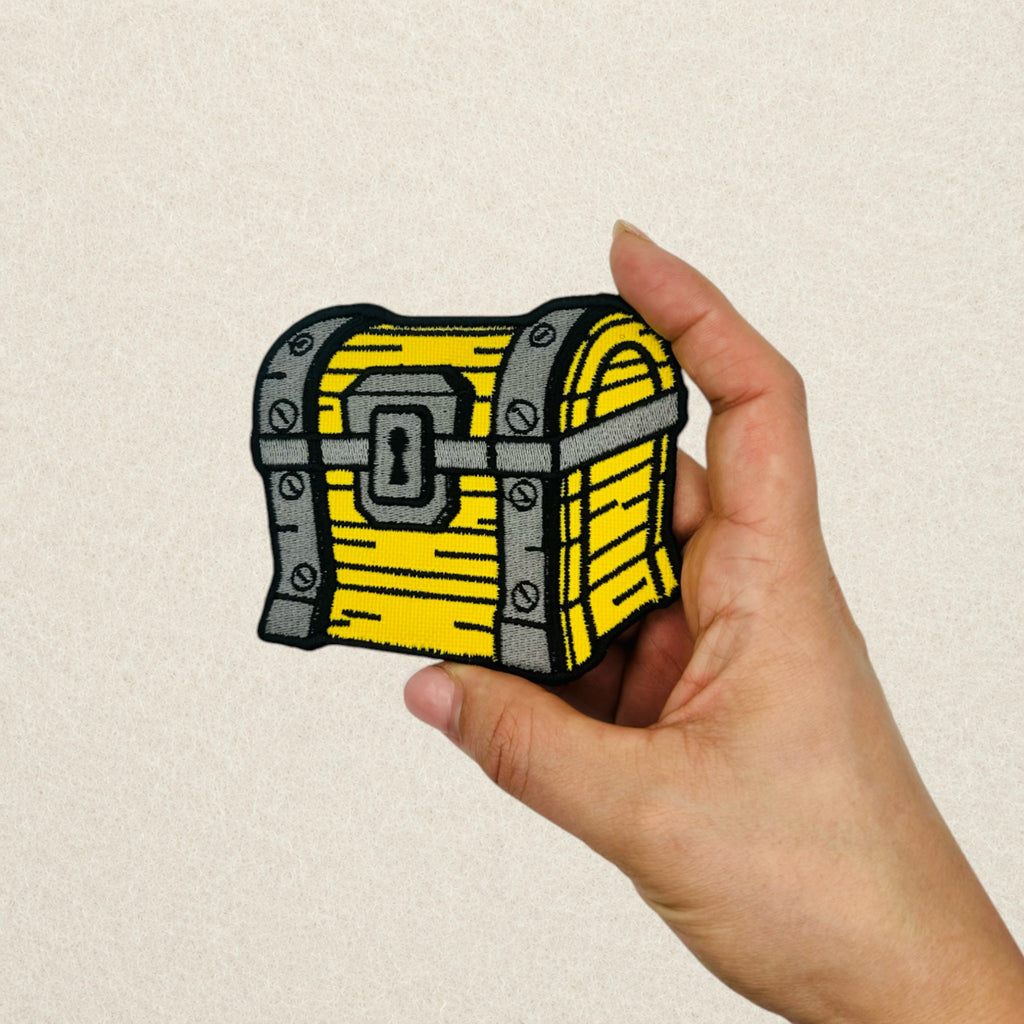 Treasure chest embroidered patch held in hand to showcase the size, stitching quality and detail of a custom embroidered patch.